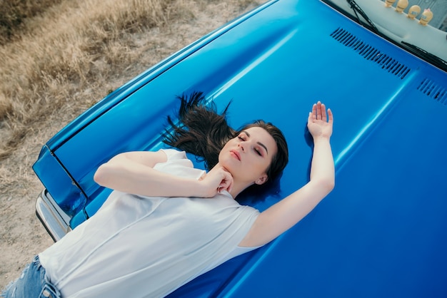 Mujer con cabello oscuro y un clásico auto convertible azul en Turquía