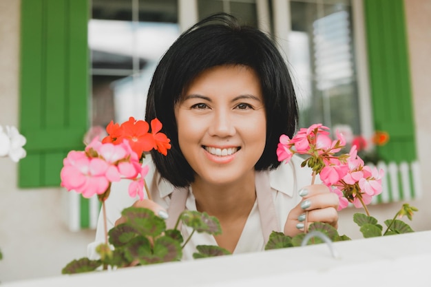 Mujer con cabello oscuro regando plantas en macetas geranios al aire libre