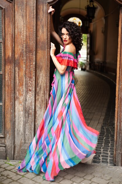 Foto mujer con cabello oscuro rizado en un vestido de verano en la ciudad