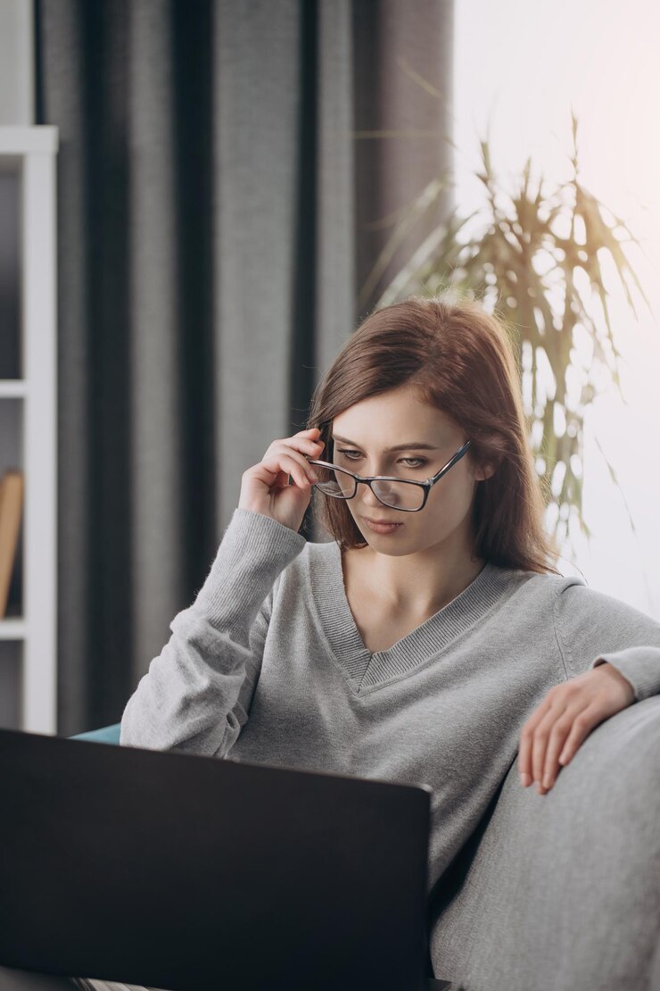 Mujer de cabello oscuro seria que usa una computadora portátil para el trabajo remoto