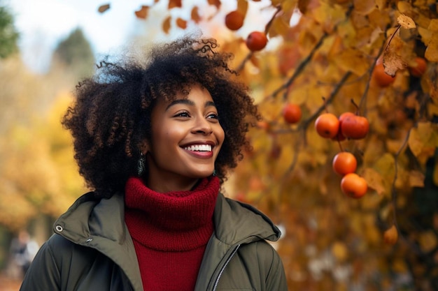 una mujer con cabello rizado se para frente a un árbol con hojas de otoño