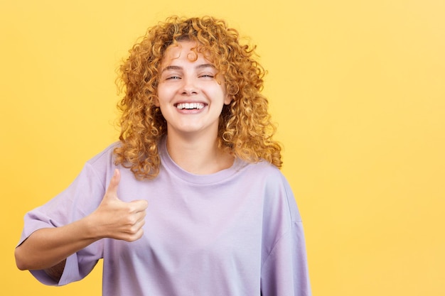 Mujer con cabello rizado gesticulando acuerdo levantando el pulgar