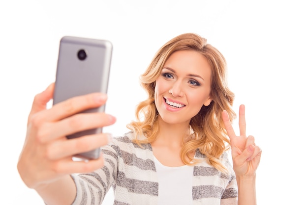 Mujer con cabello rizado haciendo selfie y mostrando dos dedos