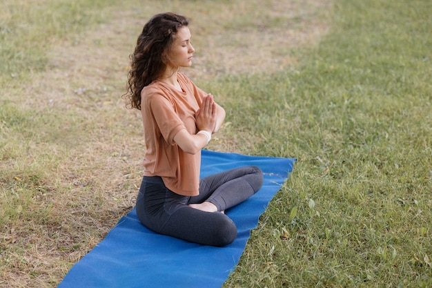 Mujer con cabello rizado medita en un parque yoga y meditación para la salud física y mental