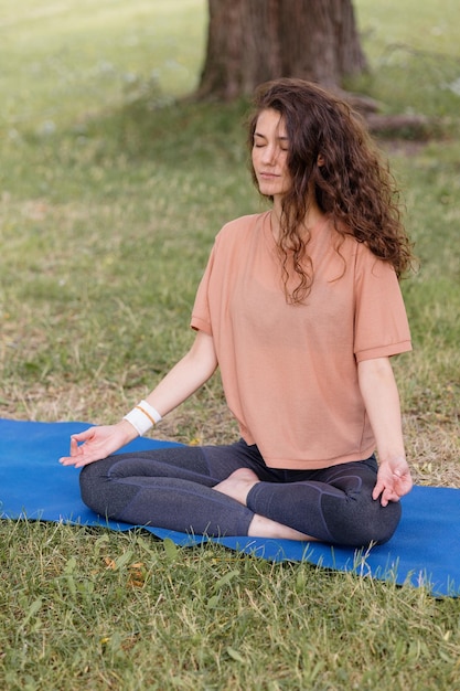 Mujer con cabello rizado medita en un parque yoga y meditación para la salud física y mental