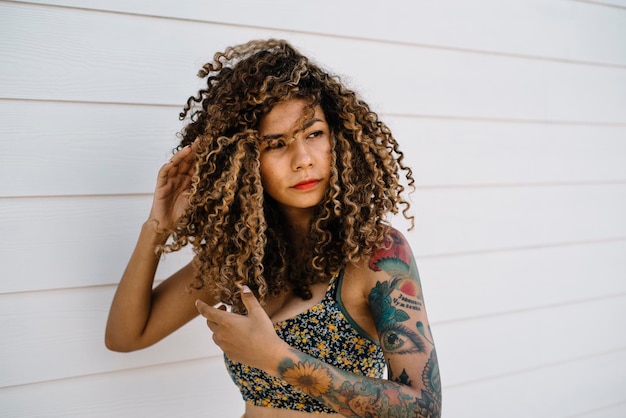 Foto mujer con el cabello rizado de pie contra la madera