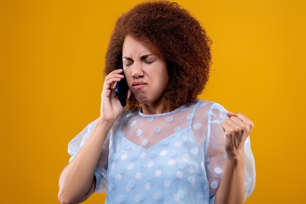 Foto una mujer de cabello rizado que tiene una llamada telefónica y se siente disgustada