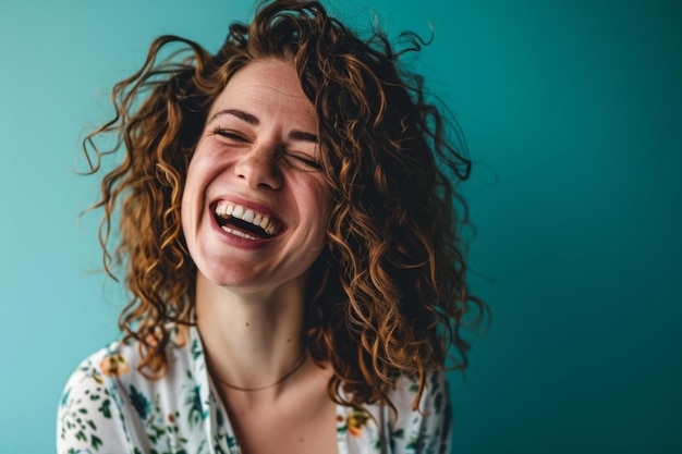 Una mujer con cabello rizado riendo frente a un fondo azul.