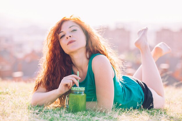 Mujer de cabello rojo bebiendo un jugo vegano natural