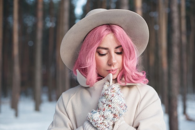 Mujer de cabello rosa mirando hacia abajo al aire libre en la nieve en un día frío de invierno. Concepto de tristeza y soledad