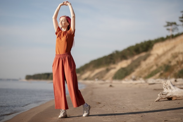 mujer con cabello rosado disfrutando del sol y el viento en la playa