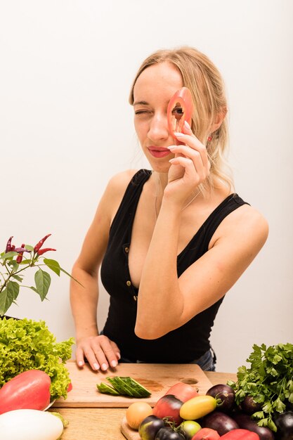 Mujer con cabello rubio corta verduras en la mesa de la cocina