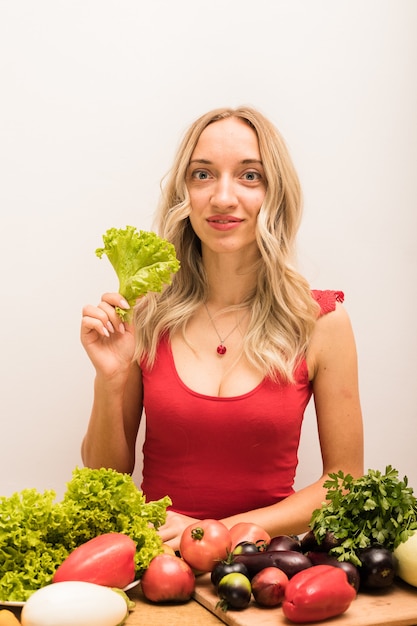 Mujer con cabello rubio corta verduras en la mesa de la cocina