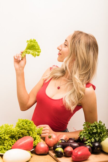 Mujer con cabello rubio corta verduras en la mesa de la cocina