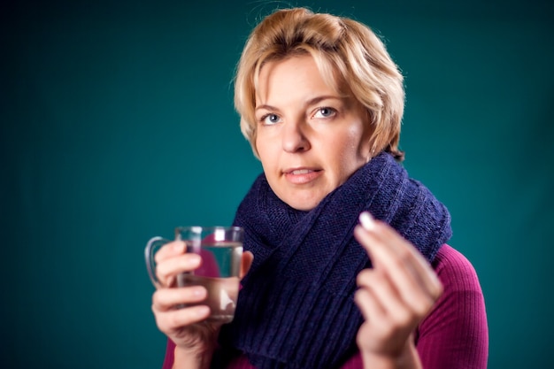 Mujer con cabello rubio corto contrajo gripe y tomando una pastilla. Concepto de personas, salud y medicina