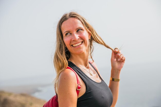 Foto una mujer con el cabello rubio largo está sonriendo y sosteniendo su cabello hacia atrás