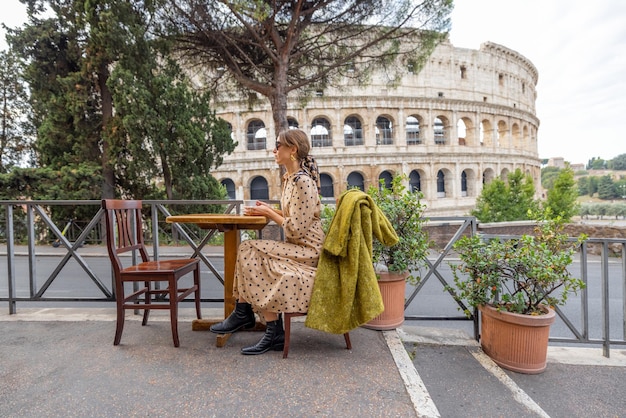 Mujer en un café al aire libre frente al coliseo en roma italia