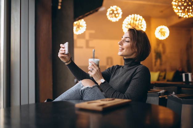 Mujer en café haciendo selfie y tomando café