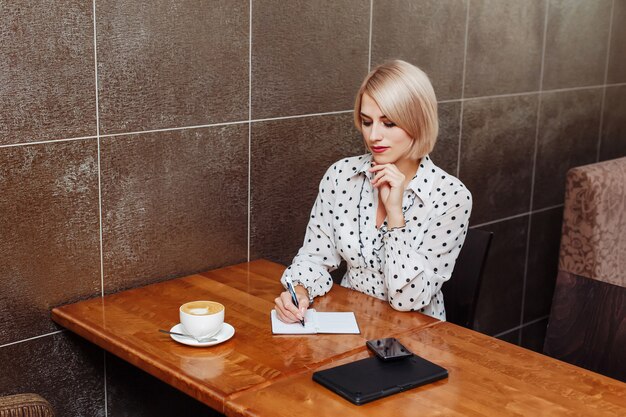 Mujer en café sentado y escribiendo en el cuaderno