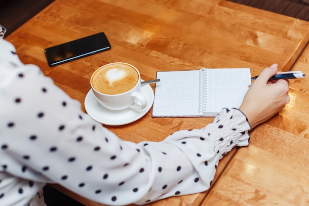 Mujer en café sentado y escribiendo en el cuaderno