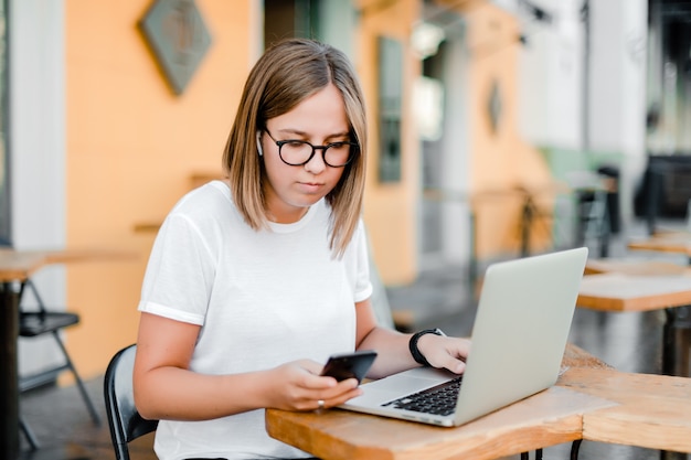 Mujer en café con teléfono y computadora portátil