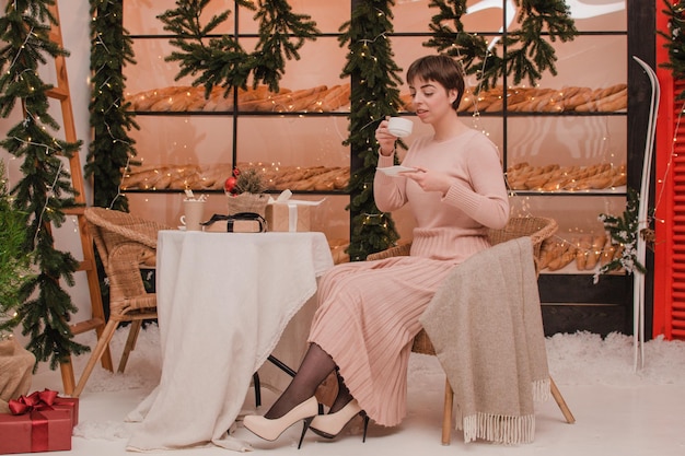 Una mujer en una cafetería bebe café o té. Concepto de Navidad y año nuevo.