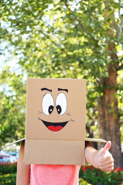 Foto mujer con caja de cartón en la cabeza con cara feliz al aire libre