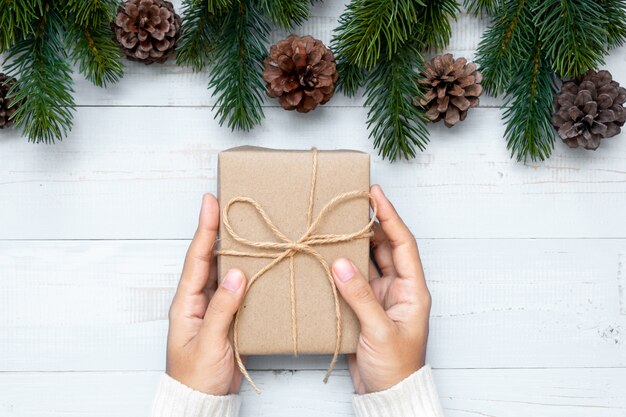 Mujer con caja de regalo con decoración navideña y ramas de pino