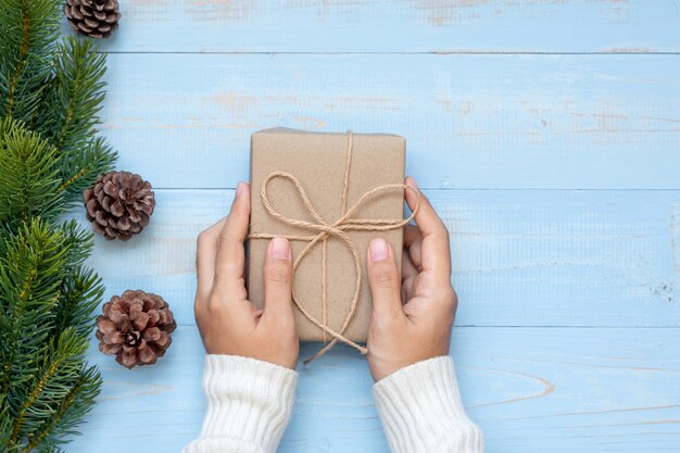 Mujer con caja de regalo con decoración navideña y ramas de pino