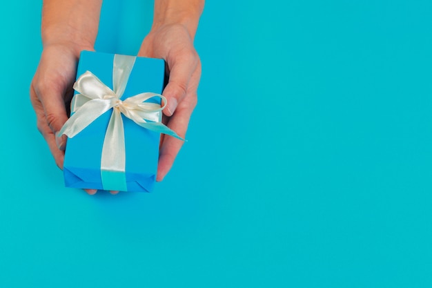 Mujer con caja de regalo sobre fondo de color