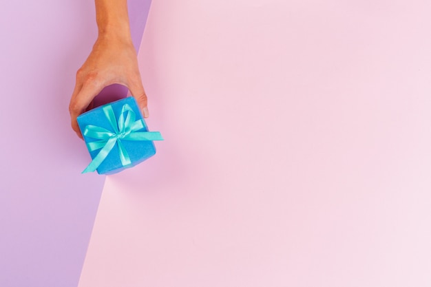 Mujer con caja de regalo sobre fondo de color