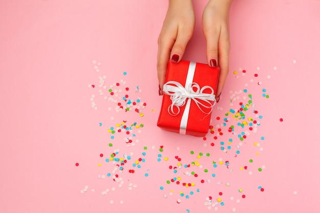 Mujer con caja de regalo sobre fondo de color