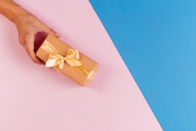 Mujer con caja de regalo sobre fondo de color