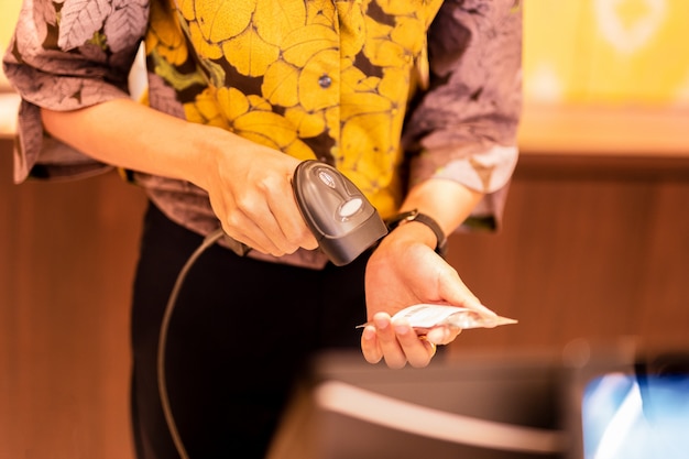 Mujer en la caja registradora escaneando el código de barras de una etiqueta