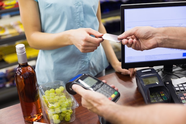 Mujer en caja registradora pagando con tarjeta de crédito