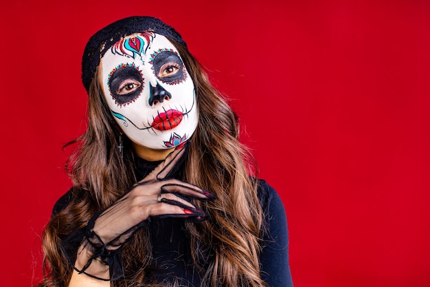 Mujer con calavera pintada en la cara para México D a de Muertos Ritual tradicional mexicano en fondo rojo de estudio
