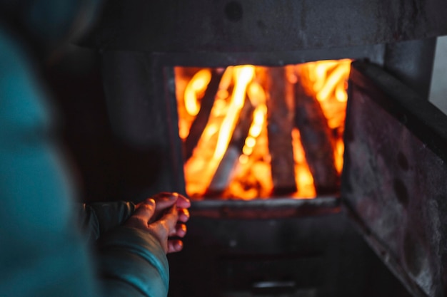 Mujer calentando cerca de una chimenea en una choza