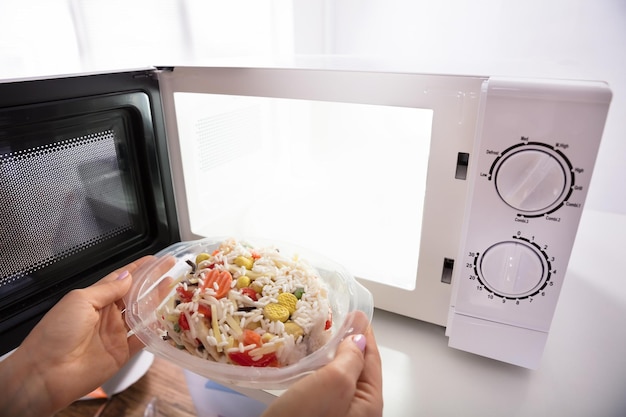 Mujer calentando comida en horno microondas