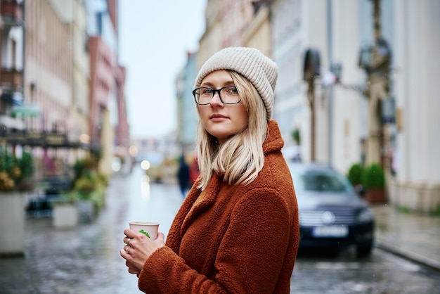 Mujer en la calle de la ciudad con taza de café