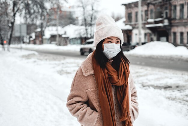 Una mujer en la calle en invierno protege el tracto respiratorio de la epidemia de coronavirus