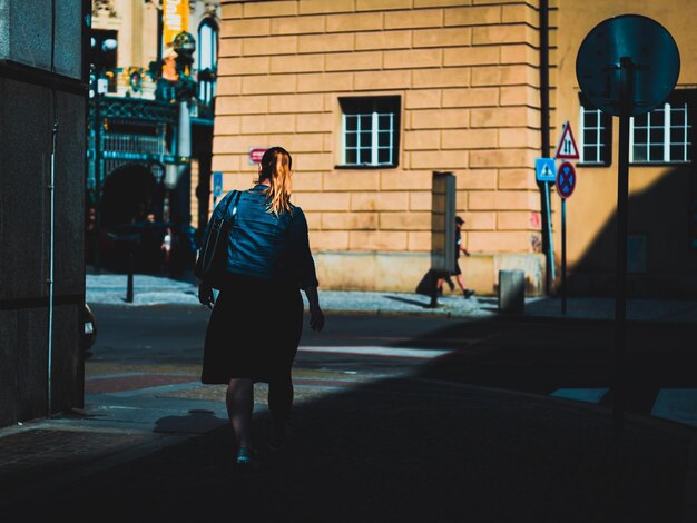 Foto mujer en una calle parcialmente iluminada