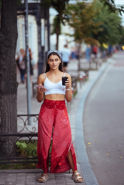 Mujer en la calle tomando café por la mañana y usando un teléfono inteligente