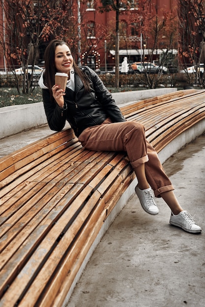 mujer en la calle con un vaso de papel desechable. Comida para llevar, pasear por la ciudad.