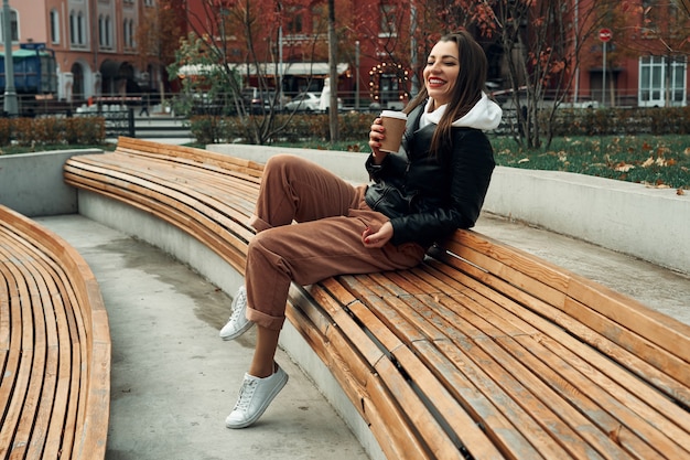 mujer en la calle con un vaso de papel desechable. Comida para llevar, pasear por la ciudad.