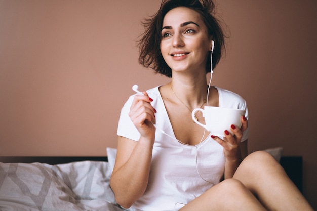 Mujer en la cama con café y teléfono