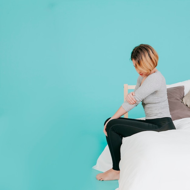 Foto mujer en la cama con codo lastimado