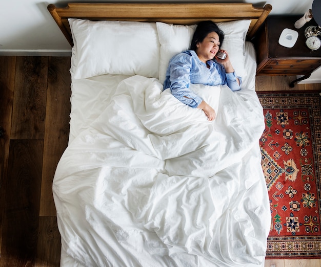 Mujer en la cama hablando por teléfono