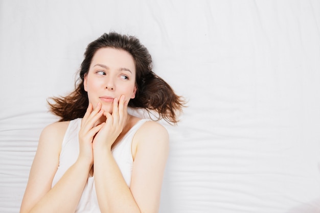 mujer en la cama sobre una sábana blanca con diferentes emociones