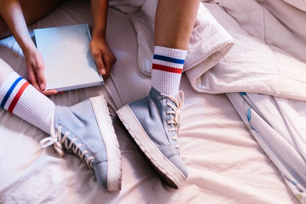 Mujer en la cama con zapatillas azules en casa comenzando a leer un libro