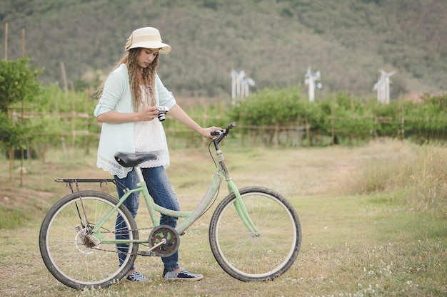 Mujer con cámara vintage en mano y bicicleta